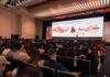 Genesys y Meta impulsan la IA agéntica en WhatsApp Auditorio completo en el Genesys Xperience observando una diapositiva sobre la "Orquestación de Experiencias" y la integración avanzada con WhatsApp.