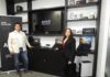 AMD y Lenovo impulsan PC con IA para PyMEs César Hernández de Lenovo y Gabriela Alvarado de AMD posando en el centro de experiencia junto a un mostrador de notebooks ThinkPad frente a una pantalla con el lema "AMD Advancing AI".