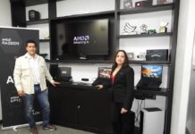 AMD y Lenovo impulsan PC con IA para PyMEs César Hernández de Lenovo y Gabriela Alvarado de AMD posando en el centro de experiencia junto a un mostrador de notebooks ThinkPad frente a una pantalla con el lema "AMD Advancing AI".