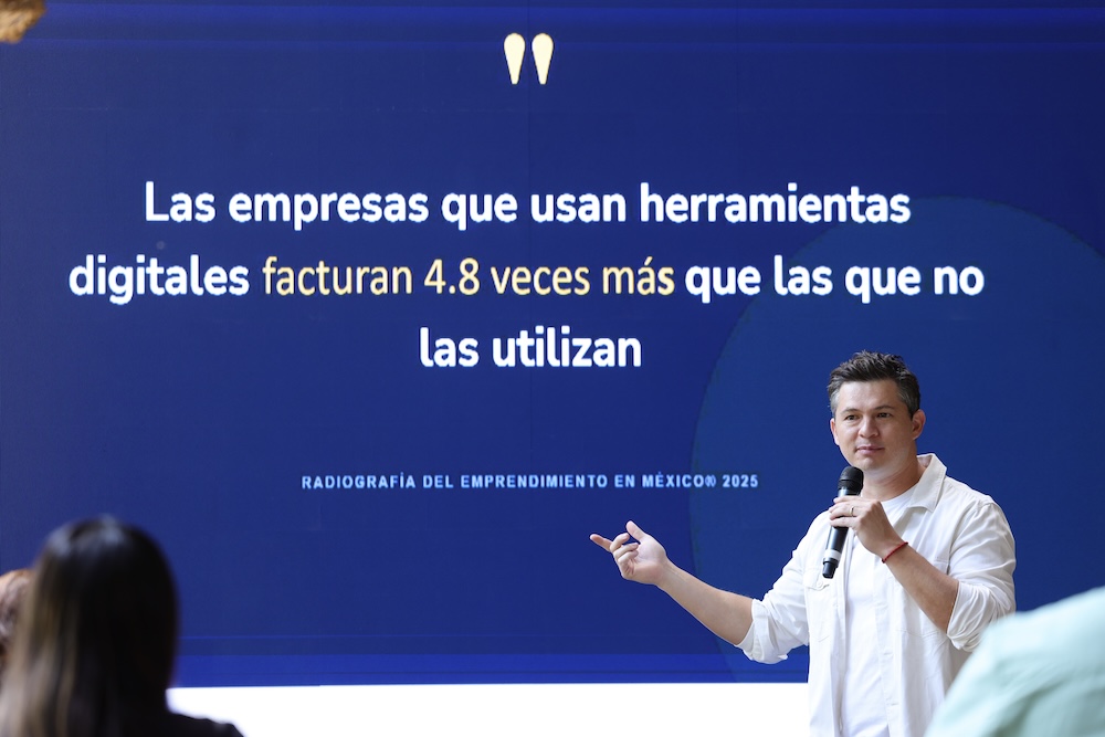 David Ortiz, CEO para Siigo Aspel Latam, hablando con micrófono en mano frente a una pantalla azul que proyecta el dato estadístico sobre cómo las empresas digitalizadas facturan 4.8 veces más.