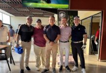 CVA acelera proyectos tecnológicos con una nueva estrategia de canales Cinco directivos y ejecutivos de Grupo CVA posan de pie, sonrientes y alineados en un área techada junto a un campo de golf durante un evento deportivo institucional. Visten ropa deportiva de golf con playeras tipo polo en tonos negro, guinda, azul marino y lila, pantalones claros y oscuros, gorras y tenis, situados al lado de un banner publicitario del torneo.