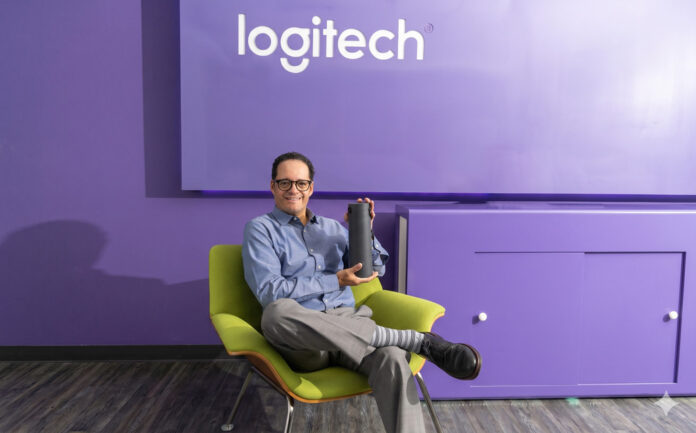 Jorge Parra, Head de Logitech for Business México, sostiene un dispositivo de comunicación en un entorno moderno diseñado para la videocolaboración.