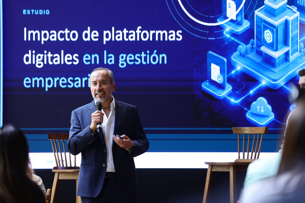 Fotografía de Juan Carlos Cante, Presidente del Consejo Directivo de la ASEM, hablando con micrófono en mano en un escenario frente a una gran pantalla con texto sobre el estudio de impacto digital.
