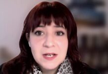 Select: Ventas TIC repuntan en julio y el optimismo empresarial alcanza su mejor nivel desde febrero Primer plano de la analista Tania Álvarez, de la firma Select, participando en una transmisión digital en vivo. Aparece hablando de frente, con el cabello castaño con flequillo, vistiendo una bufanda con estampado de leopardo y un fondo de oficina difuminado.