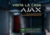 Tecnosinergia: Casa Ajax redefine la experiencia de seguridad inteligente Flyer promocional digital de Casa Ajax que muestra la entrada de una residencia moderna e iluminada de noche, equipada con sensores de seguridad en sus muros. El gráfico incluye textos superpuestos que invitan a vivir una experiencia inmersiva con tecnología real y un botón en la parte inferior para agendar visitas con clientes.
