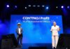 Profit 2026: CONTPAQi y Banorte aceleran digitalización financiera para PyMEs Fotografía completa tomada desde la base del escenario principal del auditorio, el cual se encuentra iluminado por reflectores superiores en tonos azules y blancos. En la tarima, René Torres posa a la izquierda con un traje azul marino, pajarita roja y sombrero de paja claro, mientras que Marlene García se ubica a la derecha exponiendo en un traje sastre formal de color rosa pálido con un apuntador digital en la mano. A sus espaldas, una pantalla gigante de color azul brillante proyecta en letras blancas el logotipo "CONTPAQi Profit® AÑOS IMPULSANDO MÉXICO" envuelto en efectos visuales de humo.
