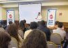 CT Internacional impulsa al canal TI con la Ruta CT Business & Training 2026 en el Bajío Fotografía que muestra una sala de conferencias con un conferencista de pie hablando frente a una audiencia sentada de espaldas. El ponente, un hombre de camisa blanca y pantalón oscuro, sostiene un micrófono inalámbrico. A los lados de la pantalla de proyección se ubican dos tótems publicitarios azules con el logotipo de CT Internacional y la leyenda "RUTA 2026". En la pantalla se proyecta una presentación con el título "MITO 2: LOS ANTIVIRUS SON OBSOLETOS" al lado del imagotipo de la marca ESET.
