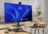 Dell lanza webcams con IA y reconocimiento facial 4K y 2K para trabajo híbrido Fotografía de estudio con fondo blanco que muestra la cámara web Dell Pro 5 Webcam 2K (WB526) vista de frente y montada sobre un soporte de clip negro. El dispositivo tiene un diseño cilíndrico compacto de color negro mate con un lente central circular de vidrio texturizado y un pequeño indicador LED a la izquierda. El soporte inferior articulado permite fijar la cámara de manera segura sobre el borde superior de un monitor de computadora o pantalla de portátil.