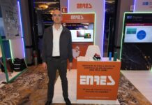 Plásticos Enres: innovación en ducto de polietileno de alta densidad para infraestructura crítica Fotografía de plano entero que muestra a Ricardo Ezeta, director operativo de Plásticos Enres, posando de pie junto al módulo comercial de su empresa en el congreso América Digital 2026 en la Ciudad de México. El directivo, calvo y con lentes, viste una camisa blanca de cuello abierto, una chamarra casual gris oscuro, pantalón oscuro y zapatos negros. A su izquierda destaca un mostrador rectangular de color naranja con el logotipo de "ENRES" en letras blancas y la inscripción "Fabricante de tubos y ductos de polietileno de alta densidad (PAD, PEAD, HDPE). 42 años de experiencia en el mercado nos respaldan". Sobre la mesa descansan muestras cilíndricas a escala de ductos plásticos de colores. Al fondo, una pantalla digital muestra el título "Solid wall HDPE ducts and pipes" y, a la derecha, se observa el pabellón de la empresa Digitalk enmarcado con luces LED verdes.