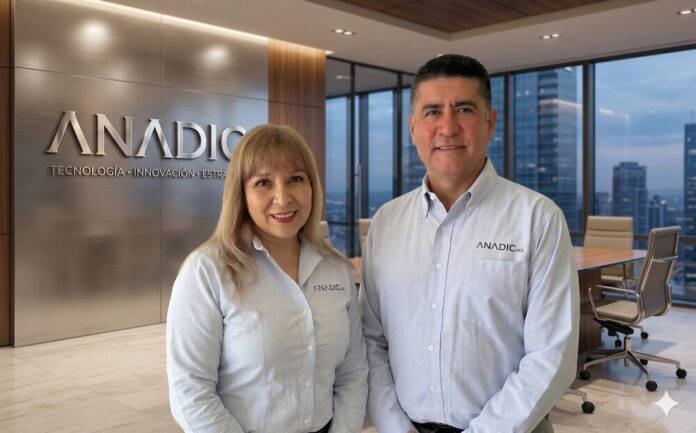 Fotografía corporativa en plano medio que muestra a Sonia Rodríguez y David Grajales posando sonrientes de pie, uno al lado del otro. Ambos visten camisas formales de manga larga de color azul claro con el logotipo de 