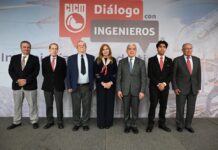 CICM: centros de datos impulsarán inversiones por 82.5 mil millones de dólares en México Fotografía en plano general que muestra a siete profesionales en fila posando de pie en un presídium frente a un gran panel publicitario. En el muro de fondo resalta un gráfico rojo en forma de bocadillo de diálogo con las siglas "CICM" y el texto en letras blancas y grises "Diálogo con INGENIEROS". El presídium está conformado por seis hombres vestidos con trajes formales oscuros y corbatas, junto a Adriana Rivera Cerecedo, quien se ubica al centro vistiendo un conjunto de pantalón oscuro y su pañuelo característico de cerezas.