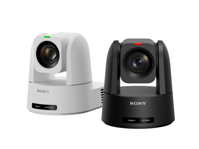 Fotografía de producto en plano medio que muestra dos cámaras robóticas PTZ compactas de Sony dispuestas una al lado de la otra sobre un fondo blanco limpio. La cámara de la izquierda es de color blanco con una pequeña luz indicadora verde en la parte superior del lente, mientras que la cámara de la derecha es de color negro mate con un indicador luminoso rojo. Ambos dispositivos muestran el logotipo de 