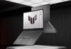 ASUS TUF Gaming A14 combina potencia para gaming y trabajo en un formato ultraligero Imagen renderizada que muestra dos laptops ASUS TUF Gaming A14 en color gris oscuro flotando sobre un panel iluminado dentro de un entorno oscuro con paredes metálicas. La computadora principal aparece abierta en primer plano, mostrando el teclado, el touchpad y la pantalla con el logotipo de TUF sobre un fondo blanco estriado. La segunda computadora flota detrás, mostrando la tapa exterior con el emblema de la marca y el diseño de la rejilla de ventilación en la base.
