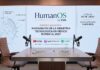 Grupo CVA lanza HumanOS by CVA para impulsar conversaciones sobre liderazgo e innovación Fotografía del set de grabación de un videopodcast. En primer plano, se observa una mesa de madera con dos sillas de oficina de cuero marrón enfrentadas y dos micrófonos articulados. Sobre la mesa hay dos placas con los nombres "Moisés Avelar - CEO Grupo CVA" y "Lourdes Baeza - Directora de Mercadotecnia Grupo CVA". Al fondo, una gran pantalla iluminada muestra el logotipo "HumanOS by CVA" y el texto "Episodio Inaugural: Radiografía de la Industria Tecnológica en México rumbo al 2027". A la izquierda de la pantalla, un gráfico de un globo terráqueo señala los conceptos "Inteligencia Artificial", "Innovación" y "Talento". A la derecha, un recuadro indica "Estreno 20 de julio" y "Nuevo episodio cada mes". En la parte inferior de la pantalla aparecen los logotipos de YouTube, Apple Podcasts y Spotify.