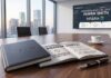 Infoblox fortalece su estrategia de ciberseguridad con el nombramiento de Henrik Smith como CISO Fotografía de una sala de juntas corporativa con grandes ventanales y vista a la ciudad. En primer plano, sobre una mesa de madera, se observa una libreta negra cerrada con el logotipo de Infoblox, un bolígrafo, una taza de café y una agenda abierta que muestra el texto "NOMBRAMIENTO DE CISO: HENRIK SMITH" junto a íconos de ciberresiliencia y gestión de riesgos. Al fondo, una pantalla de presentación proyecta el anuncio oficial del nuevo directivo acompañado de métricas y gráficas operativas.