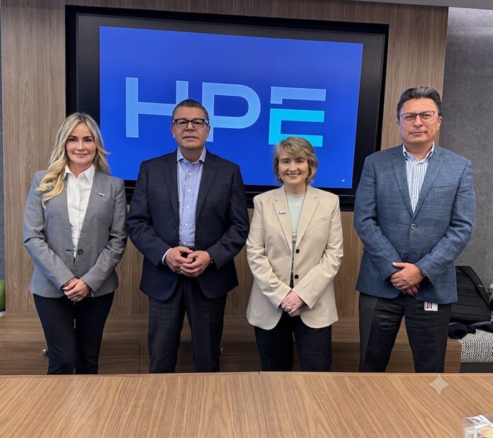 Cuatro ejecutivos de Hewlett Packard Enterprise posan de pie y sonrientes en una sala de juntas corporativa. De izquierda a derecha se encuentran Laura Gómez, Gustavo Gómez, Pamela González y Max Santiago. Al fondo, una pantalla digital enmarcada en madera proyecta el logotipo de HPE en tonos azules.