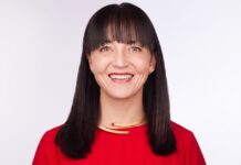 Veeam fortalece su estrategia de IA y marketing con el nombramiento de Mika Yamamoto Retrato de estudio en plano medio y de frente de Mika Yamamoto, directora de Marketing (CMO) y de IA para el cliente de Veeam Software, posando sonriente sobre un fondo blanco limpio. La ejecutiva tiene tez clara, cabello oscuro y lacio con fleco recto que enmarca su rostro, y viste una blusa formal de color rojo brillante. En su cuello resalta una gargantilla rígida dorada con un diseño asimétrico minimalista y discretas incrustaciones cuadradas de pedrería roja en los extremos.