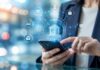 EPAM acelera la transformación empresarial y es reconocida por Databricks como Socio Global de IA 2026 Toma de primer plano que enfoca las manos de una mujer vestida con saco ejecutivo mientras utiliza un teléfono inteligente. De la pantalla del smartphone emerge una interfaz gráfica holográfica tridimensional de color azul brillante con el icono central de un banco con columnas clásicas. A su alrededor se ramifican de manera circular diversas funciones de red e iconos digitales conectados por líneas de datos, entre ellos un candado de seguridad, una señal de Wi-Fi, una tarjeta de crédito, una computadora portátil, un teléfono celular y una nube de almacenamiento, todo enmarcado en un fondo urbano con luces desenfocadas.