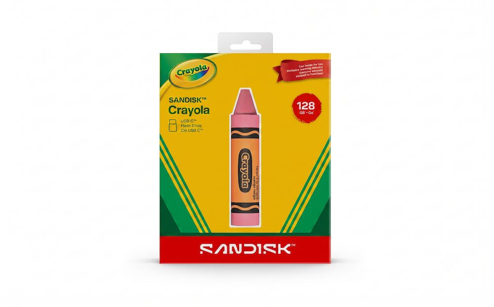 Empaque de la unidad flash USB-C SanDisk Crayola sobre un fondo blanco. El cartón de color amarillo con detalles en verde emula la clásica caja de crayones y tiene una ventana transparente en el centro que deja ver una memoria de 128 GB con la forma de un crayón de color naranja rojizo.
