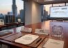 AMD y SECIHTI impulsan talento en IA y supercómputo en México Fotografía de una elegante sala de juntas con vista al Ángel de la Independencia en la Ciudad de México durante el atardecer. Sobre la amplia mesa de madera destacan documentos del acuerdo de colaboración entre AMD y SECIHTI, una pluma, identificadores institucionales y una placa de acrílico conmemorativa. Al fondo, una pantalla proyecta los logotipos de ambas organizaciones junto a un mensaje sobre innovación, mientras que en una mesa lateral se exhiben un procesador AMD EPYC y la maqueta de un servidor.