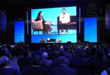 SAP NOW IA Tour México impulsa la inteligencia artificial empresarial con SAP Business AI Platform Vista desde la perspectiva del público hacia el escenario principal de SAP Now, donde se proyecta en pantallas gigantes la charla entre Adriana Aroulho y el CIO de Coca-Cola FEMSA, frente a una gran audiencia.