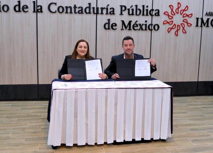 Fotografía de Rosalía Ortega López y Hans L. Schmal sentados detrás de una mesa con mantel blanco, sosteniendo y mostrando a la cámara las carpetas abiertas con los documentos del convenio recién firmado.