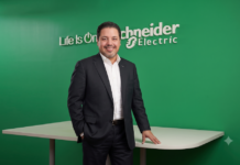 Schneider Electric: La IA redefine el negocio del canal TI; la oportunidad está en los servicios gestionados Fotografía de José Alberto Llavot, Gerente de Preventa y Desarrollador de Negocios en Schneider Electric, posando de pie y sonriendo a la cámara. Viste un traje oscuro con camisa blanca sin corbata, apoyando una mano sobre una mesa blanca frente a una pared verde brillante que exhibe el logotipo tridimensional de la compañía con el lema "Life Is On".