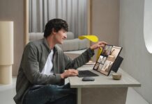 ASUS impulsa la productividad con laptops de doble pantalla Fotografía de un hombre joven sonriente utilizando una laptop ASUS Zenbook DUO sobre un escritorio minimalista con acabado de mármol. El equipo tiene sus dos pantallas desplegadas verticalmente, mostrando una galería de imágenes y herramientas de diseño. El usuario toca la pantalla superior con una mano mientras utiliza el teclado magnético separado con la otra.
