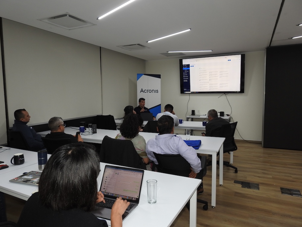 Fotografía desde la perspectiva trasera de una participante que trabaja en su computadora portátil durante una mesa de trabajo interactiva sobre ciberseguridad e infraestructura como servicio de Acronis.