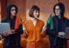 Avast revela que el 53% de los mexicanos cree detectar contenido falso pero el 65% expone sus datos a chatbots de IA Concepto visual en un entorno de oficina donde una mujer vestida con blusa naranja se encuentra entre dos figuras idénticas con sudadera negra con capucha y anteojos sosteniendo laptops; la mujer sostiene una bandera roja hacia la izquierda y una bandera verde hacia la derecha para ejemplificar la toma de decisiones frente a señales de alerta digital.