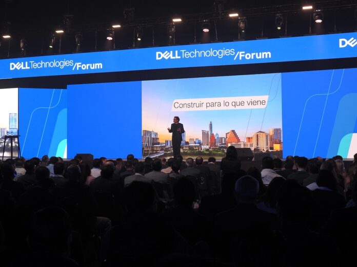 Cientos de asistentes participan en las conferencias magistrales enfocadas en la evolución de los centros de datos y el impacto de la inteligencia artificial. Fotografía panorámica tomada desde el fondo del auditorio en el Dell Technologies Forum 2026, donde una multitud escucha a un ponente en el escenario principal frente a una pantalla gigante con la leyenda
