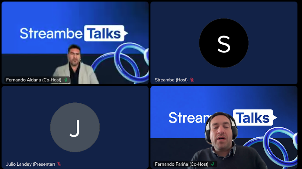 Interfaz de conferencia virtual dividida en cuatro recuadros donde se observa a Fernando Aldana y Fernando Fariña de Streambe como coanfitriones, junto a los avatares del presentador Julio Landey y el anfitrión.
