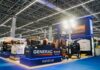 Generac impulsa la transformación energética del sector ferretero en México Fotografía en ángulo abierto del estand de exhibición de Generac en la Expo Nacional Ferretera, iluminado con luces LED azules y blancas, donde se observan diversos equipos de generación eléctrica etiquetados en módulos como "Portátiles", "Residencial" e industrials, incluyendo torres de iluminación y generadores diésel sobre un suelo azul.