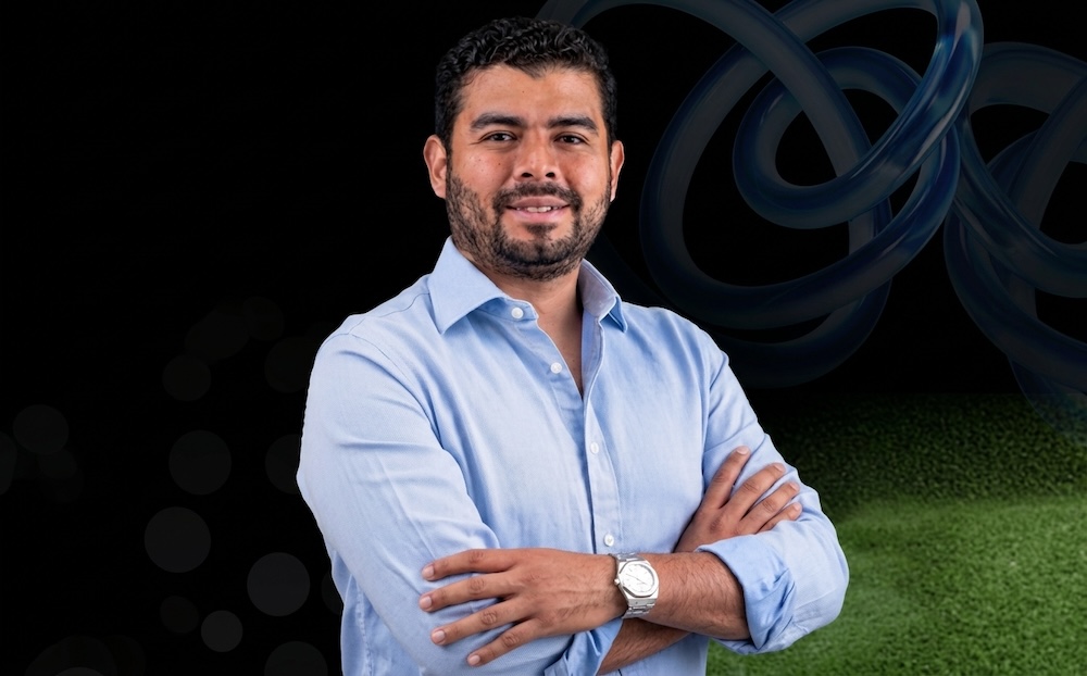 Gigas impulsa su estrategia de nube administrada para el canal de distribución en Latinoamérica Fotografía de retrato de Ezequiel Sulvarán posando de tres cuartos con los brazos cruzados. Viste una camisa de manga larga color azul claro de cuello abierto y luce un reloj metálico en la muñeca izquierda, sobre un fondo digital con tonos oscuros y elementos abstractos.