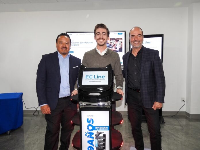 Fotografía de tres directivos sonriendo en una sala de exhibición mientras posan rodeando un robot de servicio interactivo de EC Line. El equipo robótico, de color negro con la pantalla principal iluminada, se ubica al centro, flanqueado por pantallas táctiles corporativas en el fondo.