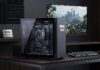 Kingston impulsará el máximo rendimiento gamer en el Gamer Day con la campaña “Yo soy Kingston FURY” Fotografía de un espacio de trabajo gamer de alta gama sobre un escritorio de madera oscura. En el centro destaca un gabinete informático de tono negro mate con cristal templado lateral que deja ver los componentes internos, incluyendo memorias Kingston FURY iluminadas. A la derecha, un monitor reproduce un videojuego con un paisaje urbano detallado, acompañado de un teclado mecánico y un mouse ergonómico, mientras a la izquierda reposa una placa metálica conmemorativa de la marca.