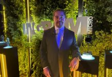 Resplandor tecnológico y negocios del futuro: la edición 30 de Los Soles de Ingram Micro Fotografía de plano medio de Gerardo Romero, director general de Ingram Micro México, posando sonriente en traje oscuro frente a un muro decorativo cubierto de follaje verde con letras metálicas iluminadas que forman la marca Ingram Micro.