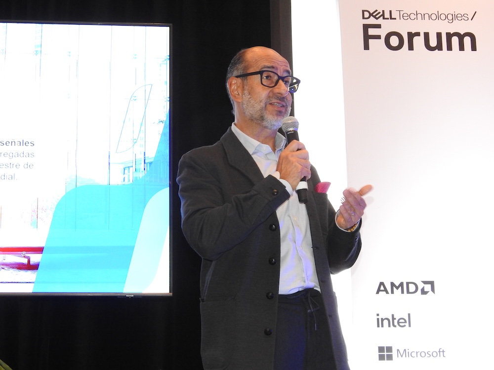 Fotografía en plano medio de Marcos Ibáñez, Director de Distribución de Dell Technologies México, vistiendo saco oscuro y anteojos, dirigiéndose al público con un micrófono en la mano durante una presentación.