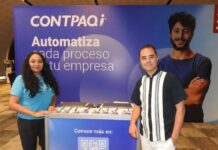 Innovación y tecnología con CONTPAQi para el impulso de las PyMEs Fotografía en plano medio de Nancy Torres y Brian Nishizaki sonriendo juntos a ambos lados de un módulo promocional de CONTPAQi con código QR y folletos institucionales.