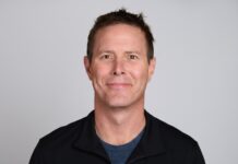 Dynatrace revela cómo la IA está redefiniendo la confiabilidad digital empresarial Fotografía de retrato de Steve Tack, vistiendo una camiseta azul oscura y una chaqueta negra, sonriendo frente a un fondo gris claro.