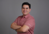 ViewSonic y su propuesta para redefinir el ecosistema del trabajo híbrido y la colaboración Fotografía de retrato corporativo de Pablo García, Gerente Regional de Negocios para México en ViewSonic, luciendo una playera polo rosa con el logotipo grabado de la marca y los brazos cruzados sobre un fondo gris neutro.