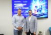 Licencias OnLine y Acronis Cyber Frame transforman el negocio de los proveedores de servicios Fotografía en plano medio de Salvador Rico, Distribution Account Manager para NOLA en Acronis, y Ernesto Jiménez, Country Sales Manager de Licencias OnLine, sonriendo juntos frente a una pantalla publicitaria de Acronis Cyber Frame.