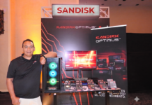El poder de Sandisk revoluciona el almacenamiento para gamers y creadores Fotografía en plano medio de Alejandro Medina, especialista en marketing y ventas de SanDisk, recargado sonriente junto a una torre de computadora con iluminación RGB en el estand de lanzamiento de la línea SanDisk Optimus.