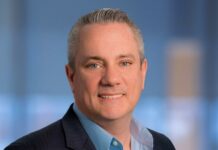 Sophos revela que los MSP asumen el rol de CISO ante los nuevos riesgos de ciberseguridad e IA Fotografía de retrato corporativo de Scott Barlow, Vicepresidente de Sophos, luciendo un saco oscuro y camisa azul claro sobre un fondo de estudio desenfocado.