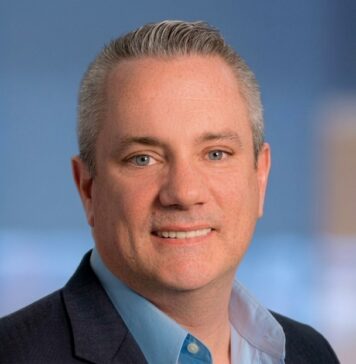 Sophos revela que los MSP asumen el rol de CISO ante los nuevos riesgos de ciberseguridad e IA Fotografía de retrato corporativo de Scott Barlow, Vicepresidente de Sophos, luciendo un saco oscuro y camisa azul claro sobre un fondo de estudio desenfocado.