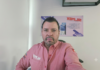 Silimex premia el éxito y desempeño de la fuerza de ventas de Grupo CVA con un viaje a Cancún Fotografía de retrato de Alfredo Álvarez Buylla, Gerente de ventas de Silimex. Aparece mirando directamente a la cámara, vistiendo una camisa de tono rosa salmón con el logotipo de la marca bordado en el pecho derecho. Al fondo, sobre una pared blanca, se observa un póster publicitario de los productos y kits de limpieza de la compañía.