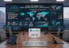 Palo Alto Networks detecta una masiva campaña de malware en YouTube dirigida a gamers y redes corporativas Fotografía en perspectiva de una sala de juntas ejecutiva con vista a la ciudad a través de grandes ventanales. En el centro de la mesa de madera hay computadoras portátiles y una placa con el logotipo de Palo Alto Networks y Unit 42. Al fondo, un videowall gigante presenta el "Informe de Investigación de Unit 42: Campaña de Malware Gaming Ghost", exhibiendo mapas globales de amenazas, gráficos de flujo de ataque e infografías estadísticas sobre la ciberseguridad en YouTube.
