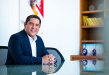 El canal ante la era de la IA y los servicios: La visión estratégica de CompuSoluciones y HP Fotografía de retrato corporativo en plano medio de Víctor Manuel Urzúa, subdirector comercial de CompuSoluciones, sonriendo con las manos entrelazadas sobre un escritorio de cristal en su oficina.
