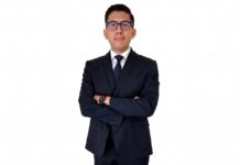 Enlace Team evoluciona su Marketplace B2B para acelerar los negocios de sus canales Fotografía de retrato en plano medio de Alberto Montiel, Gerente de Marketplace en TEAM, vistiendo traje ejecutivo azul marino con corbata a juego y anteojos, posando con los brazos cruzados frente a un fondo blanco.