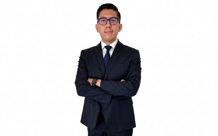 Fotografía de retrato en plano medio de Alberto Montiel, Gerente de Marketplace en TEAM, vistiendo traje ejecutivo azul marino con corbata a juego y anteojos, posando con los brazos cruzados frente a un fondo blanco.
